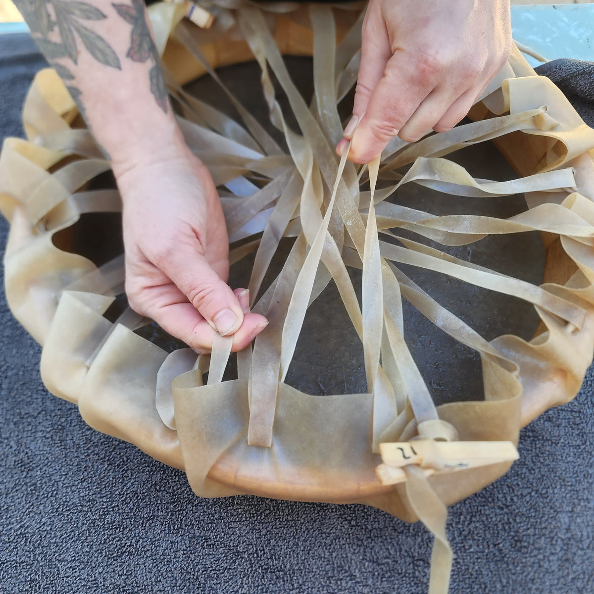 Hands weaving the lacing of a medicine drum